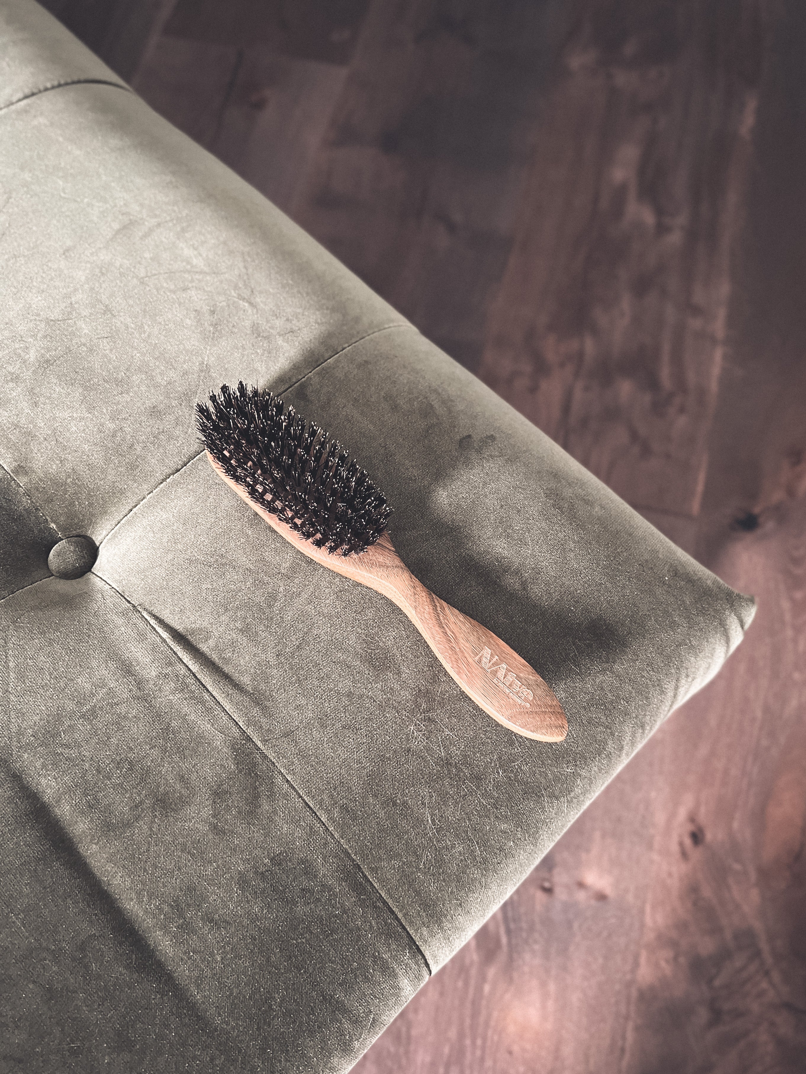 wooden boar bristle sculpting brush by natve on a gray couch with a wood floor